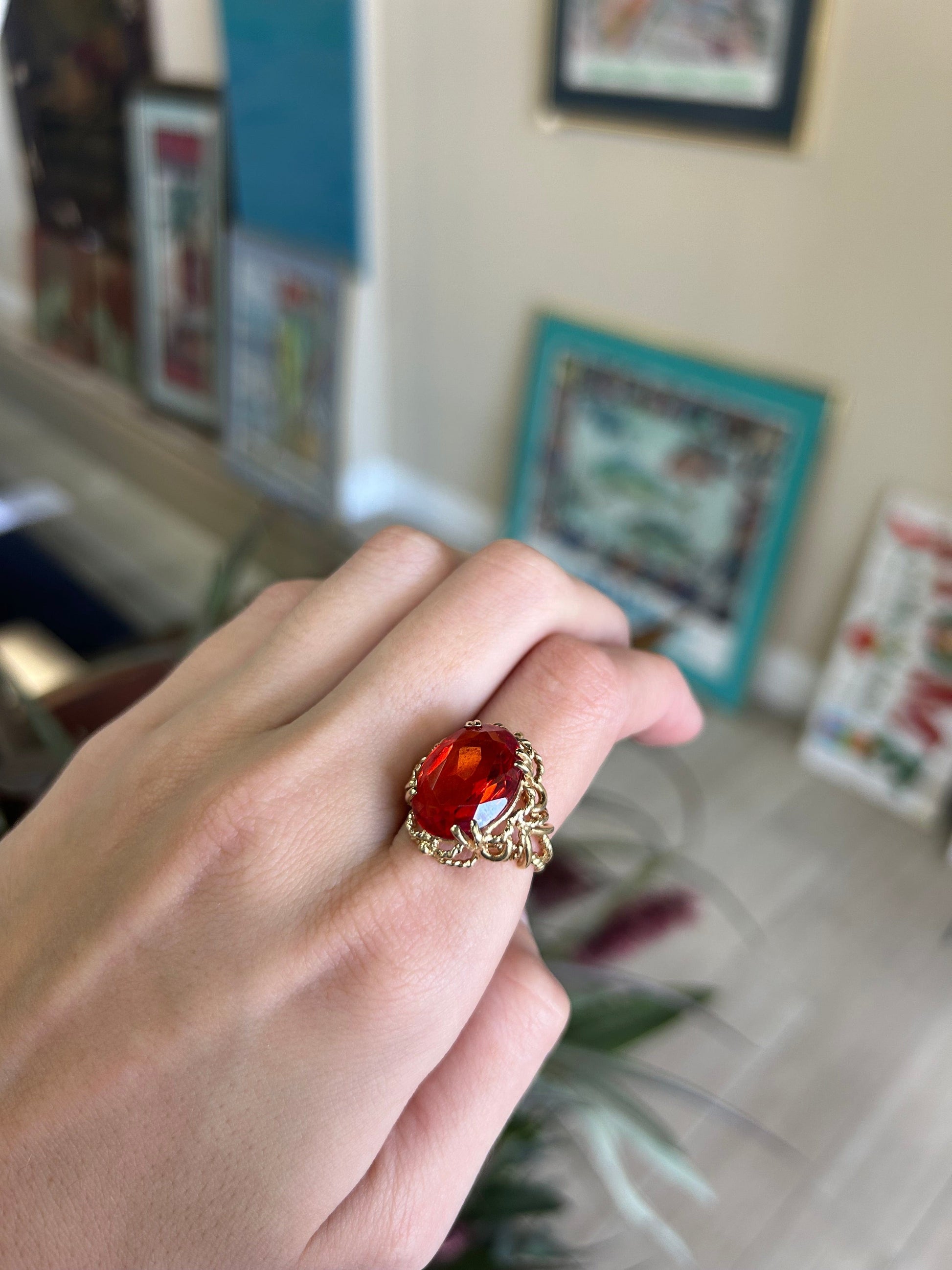 a woman's hand holding a ring with a red stone