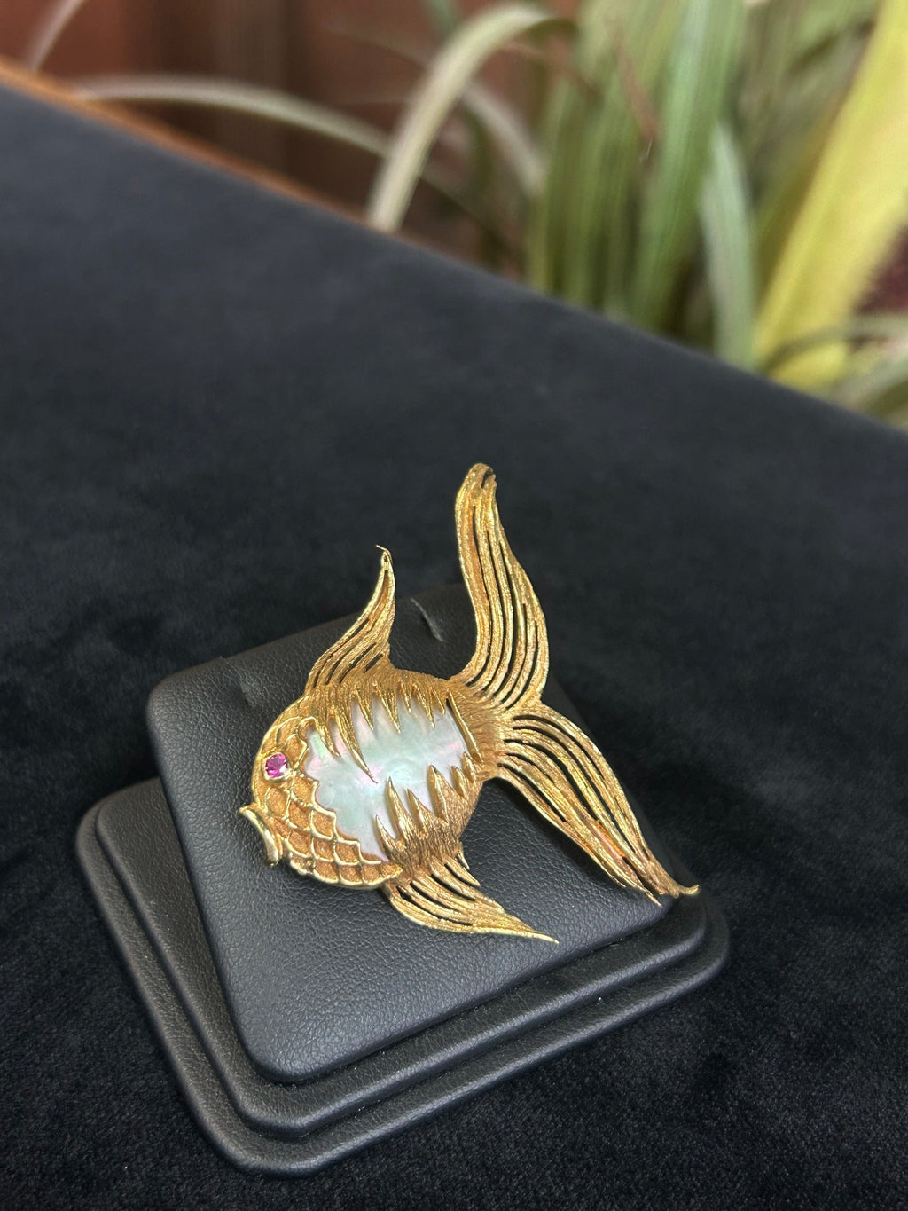 a close up of a gold brooch with a bird on it