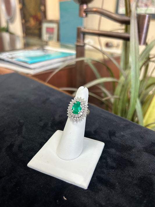 a diamond and emerald ring on a white ring holder