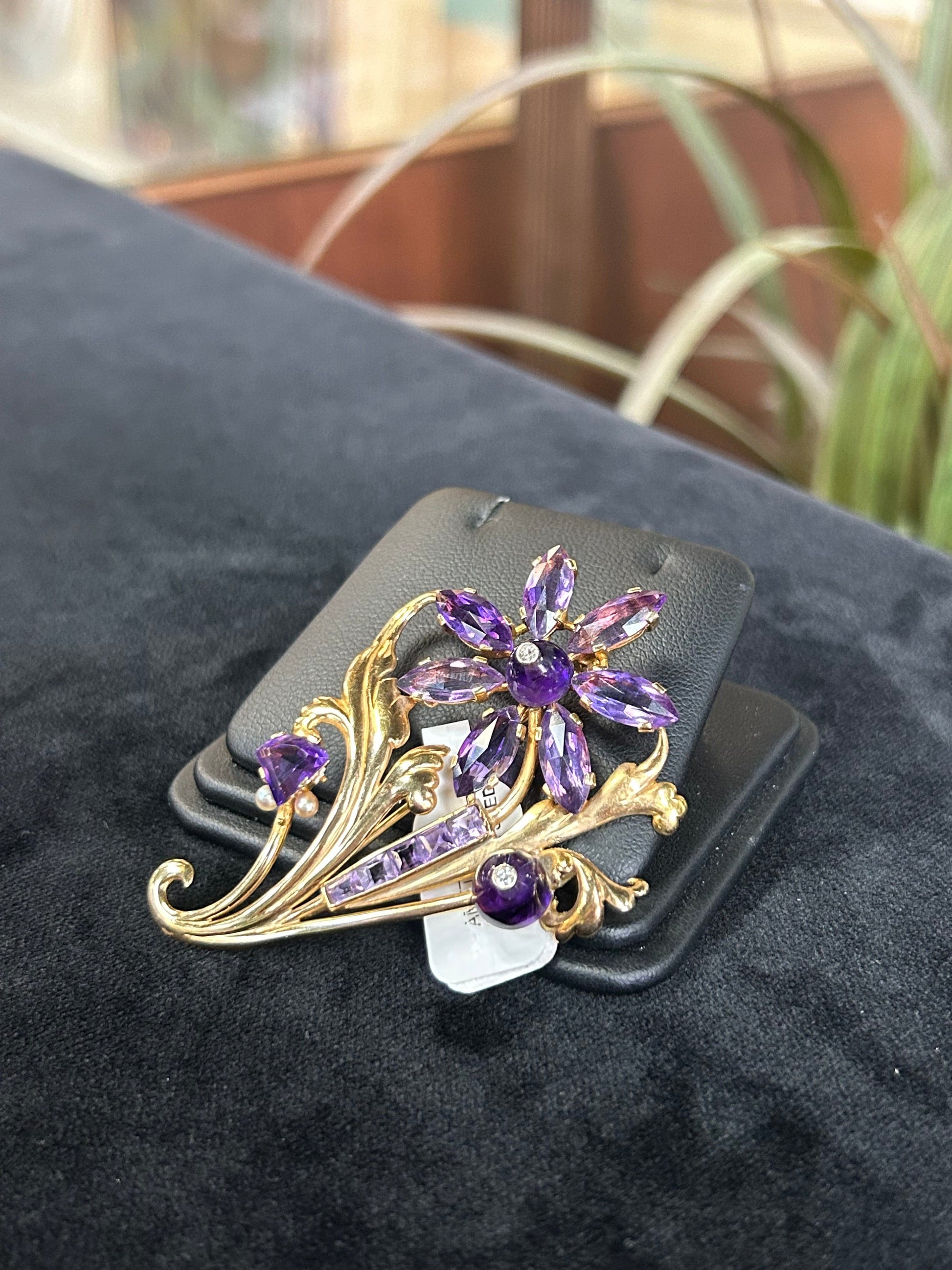 a purple flower brooch sitting on top of a black cushion
