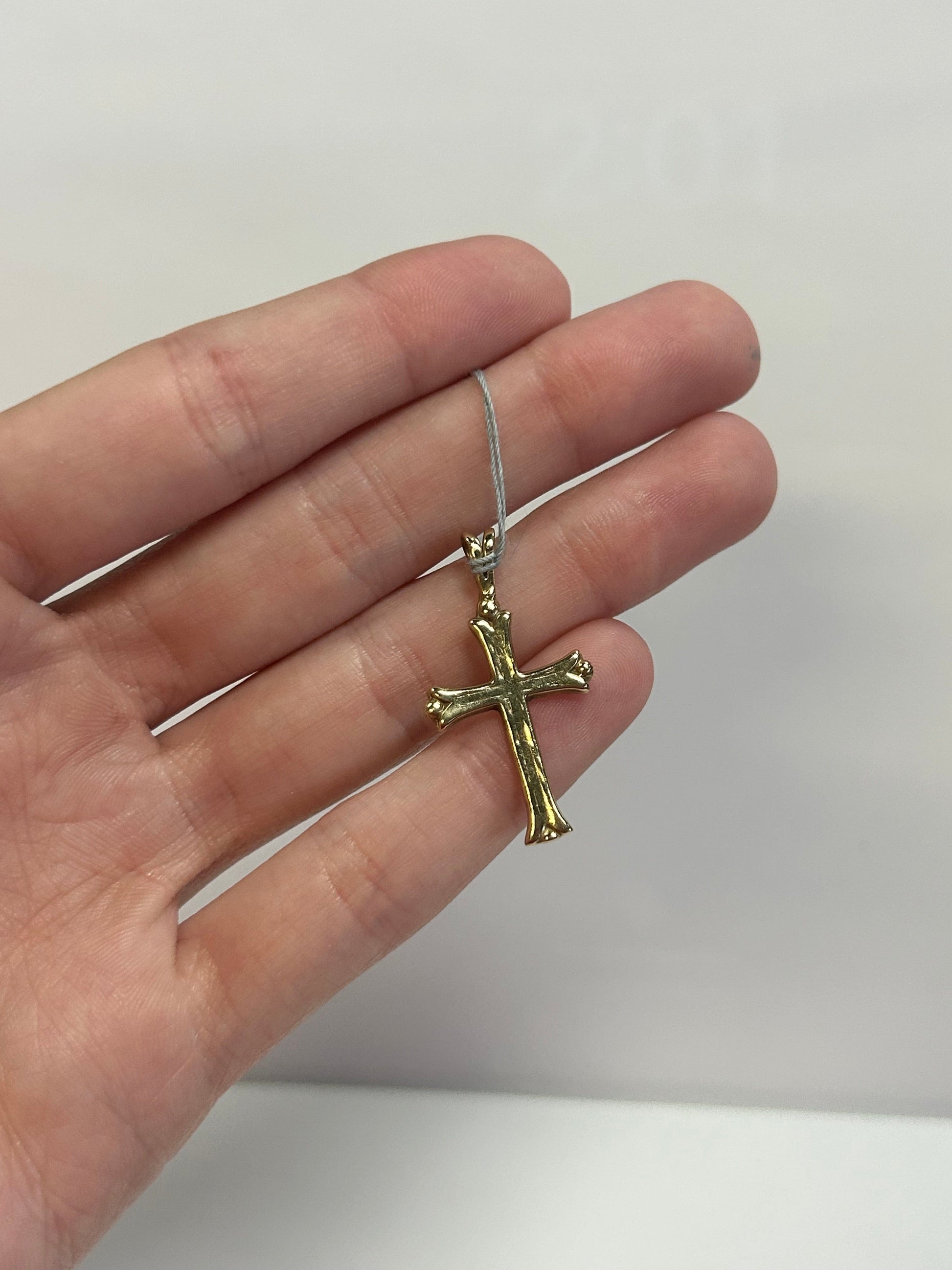 a person holding a small cross pendant in their hand
