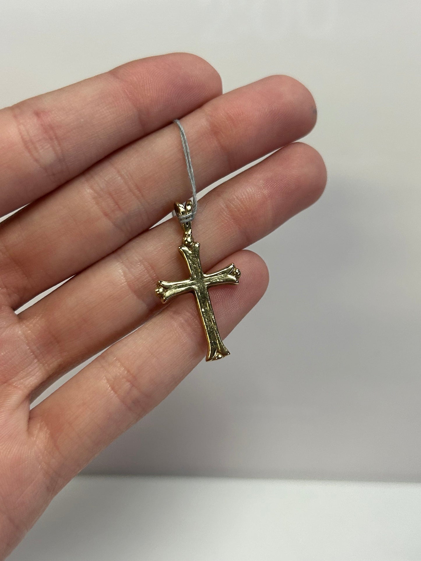 a person is holding a cross pendant in their hand