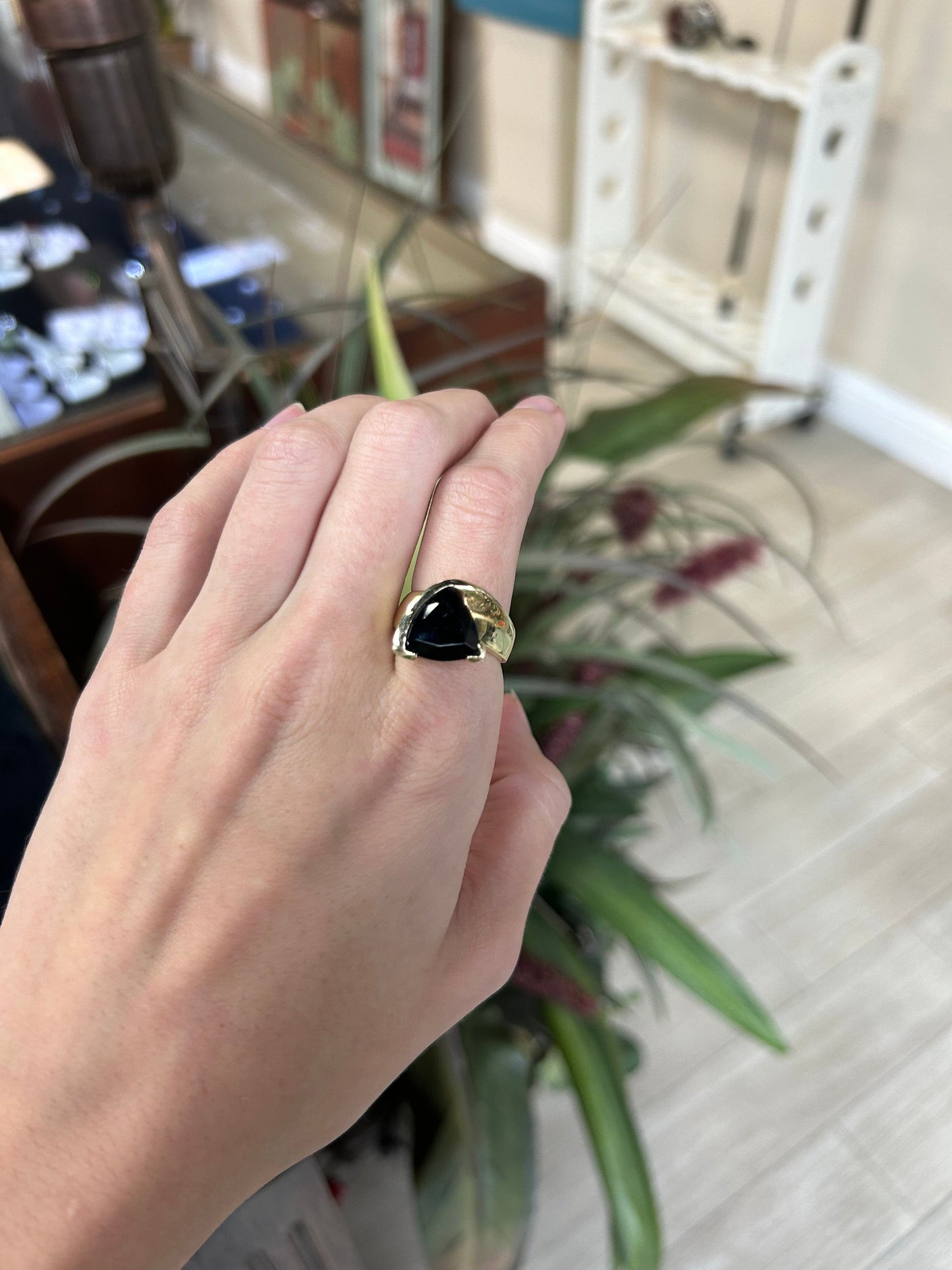 a woman's hand holding a ring with a black stone